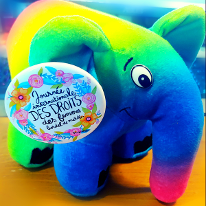 Une mascote de PHP, l'elephant, version "diversity" (aux couleurs du Pride flag) pris en photo avec un badge attaché à son oreille disant "Journée internationale DES DROITS des femmes bordel de merde !" (par Garage de l'Offre).